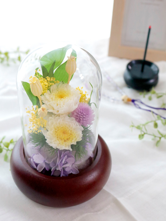 黄色、紫色などの花を使い、ガラスドームをかぶせたアレジメント