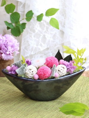 黒色の船形の器にピンク、白、紫などのお花のアレジメント