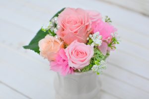 ピンク色のバラと白い小花が白い陶器の器に入ったアレンジメント
