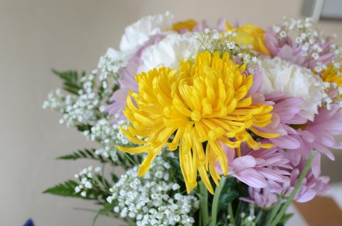 黄色・ピンク･白の菊とかすみ草を活けた花瓶