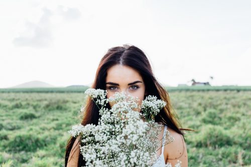 草原で白いかすみ草の花束を抱えた髪の長い女性
