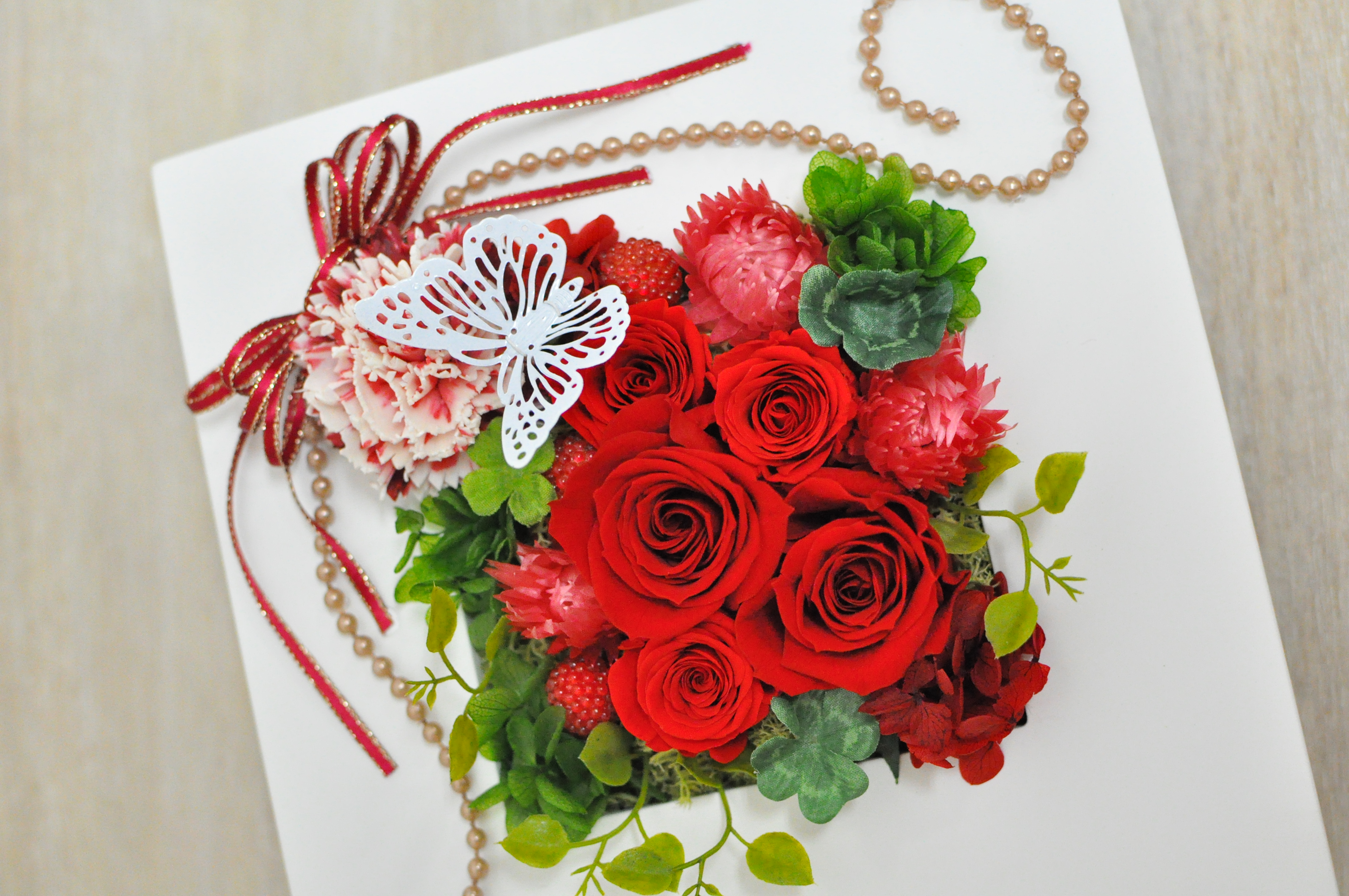 赤い花びらの花を使ったフレーム型アレンジメント