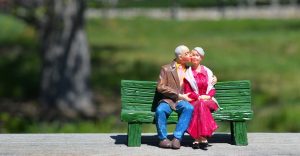 緑色のベンチにおばあさんの頬にキスをしているおじいさんのフィギュアが乗っている